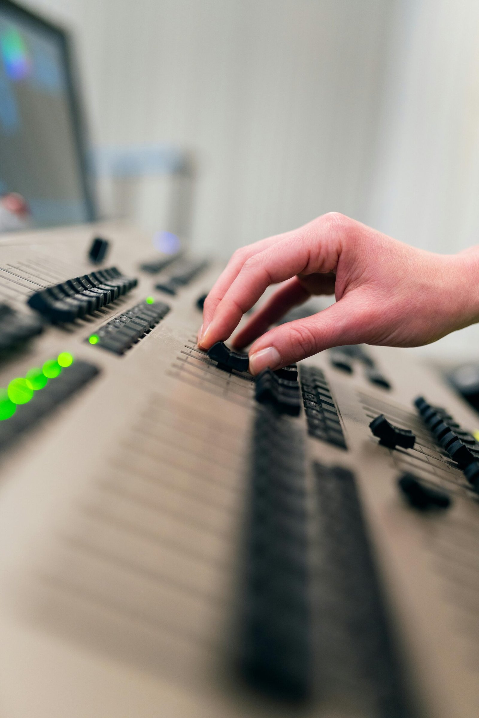 A hand adjusting sliders and knobs on a professional sound mixing console.